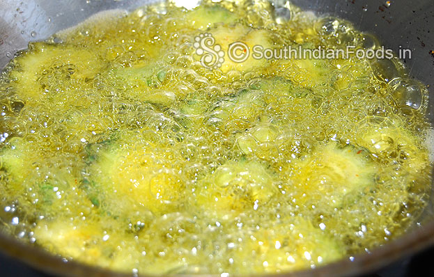 Heat oil in a pan add marinated bitter gourd slices then deep fry in medium hot oil