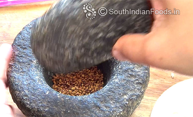 Coarsely grind with stone pestle