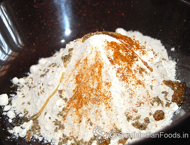 In a bowl add wheat flour, rava, ajwain, red chilli powder, turmeric powder & hot oil